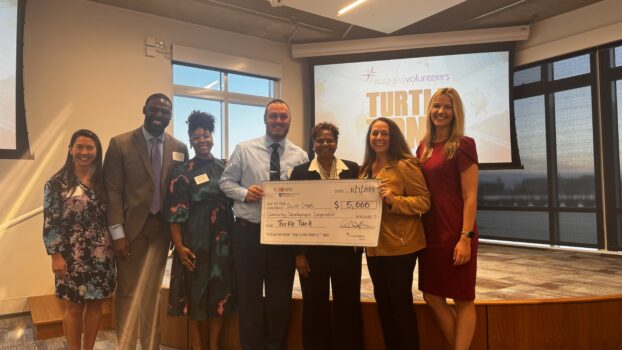 GIVE Fellows pose with the executive assistant to the Pastor of South Creek Community Development Corporation and Turtle Tank Judge Lucky Thompson holding their check for winning 2nd place.